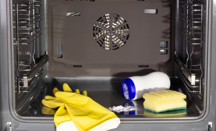 forno aperto con guanti, detergente e spugnetta