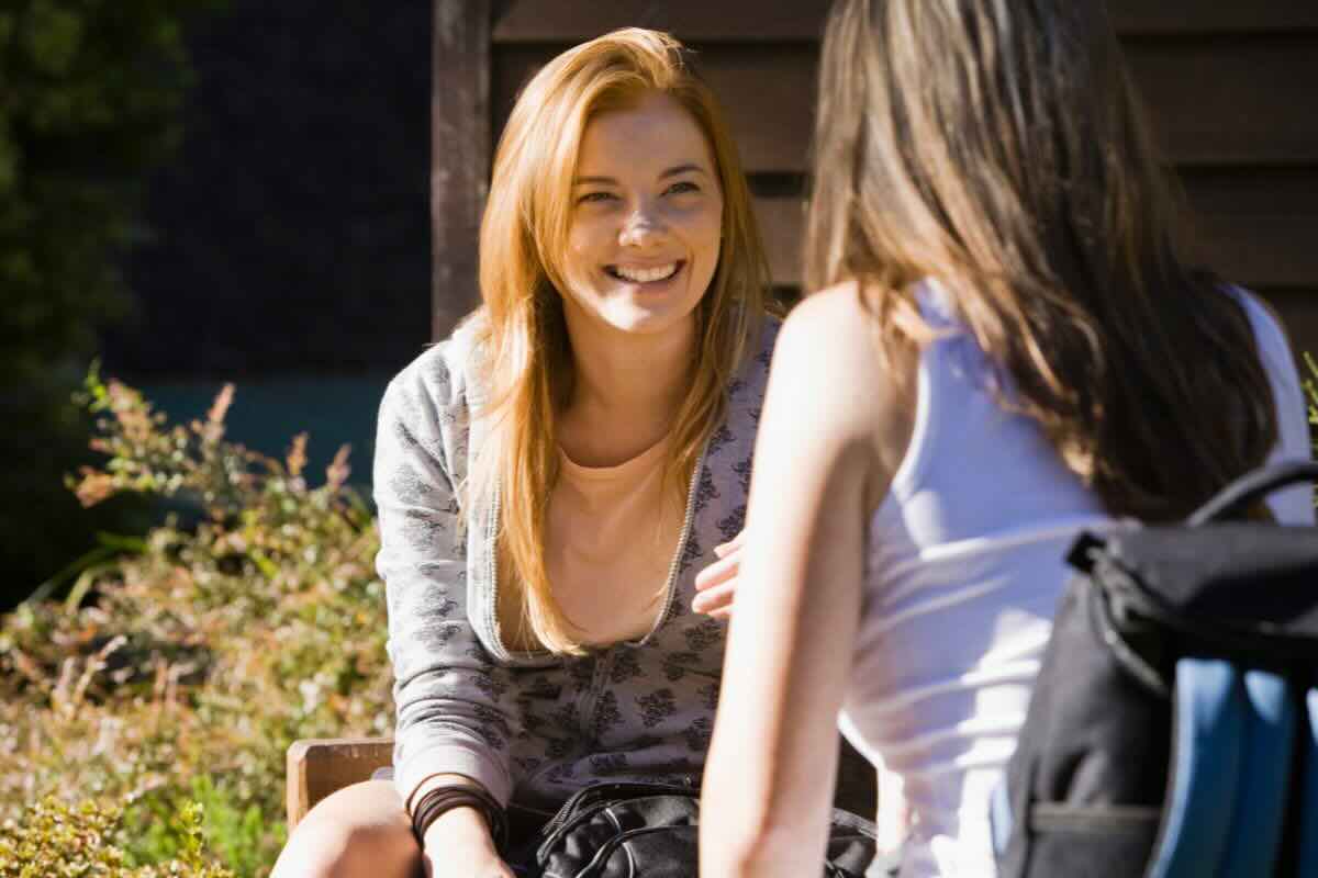 Donna sorridente dialoga con un'altra