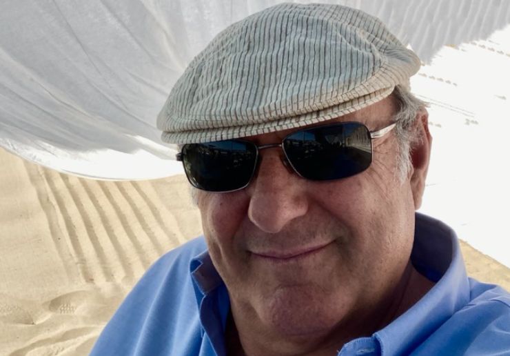 gerry scotti con un berretto e occhiali da sole