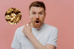 uomo scioccato con la bocca aperta che con il dito indica delle pepite d'oro
