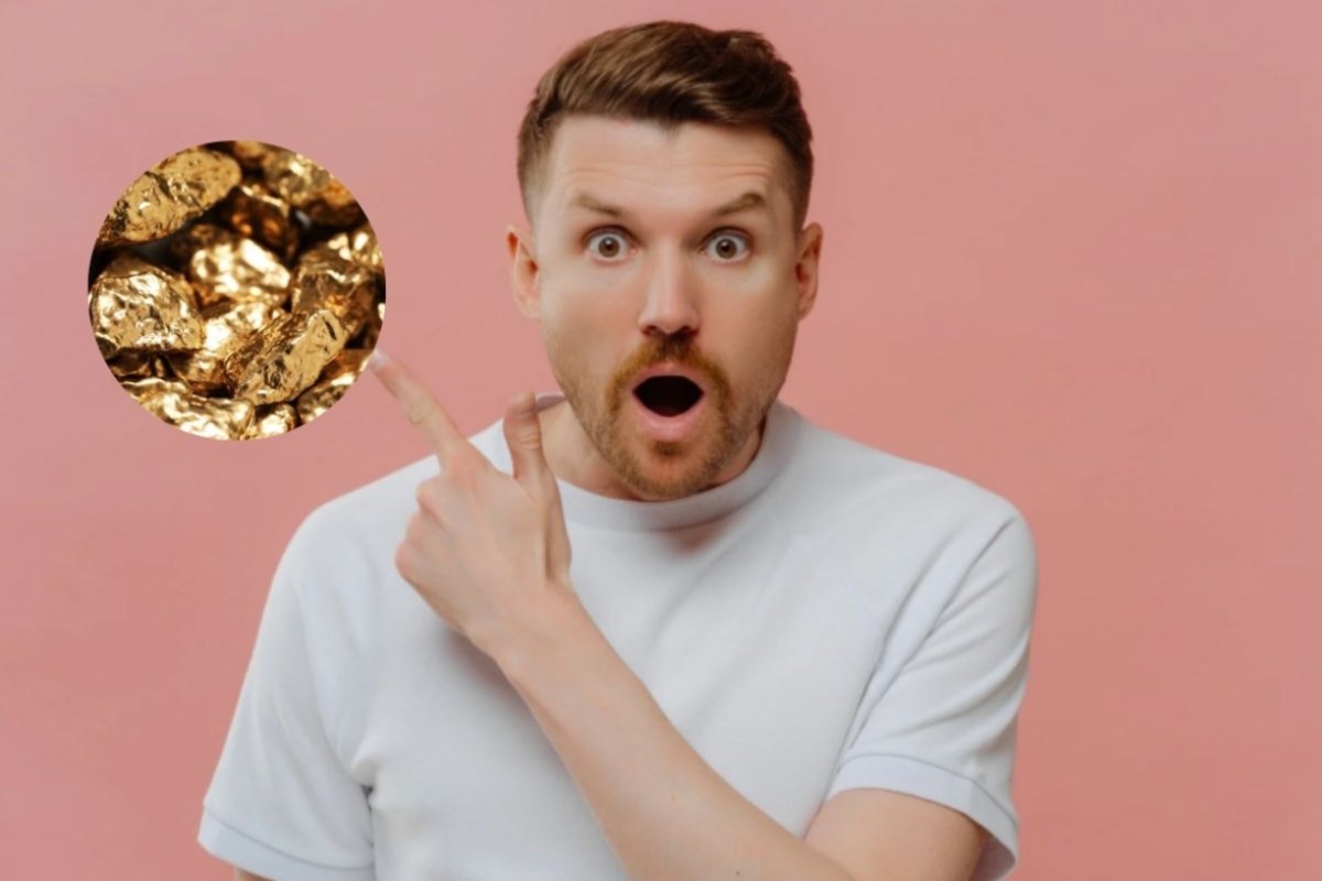 uomo scioccato con la bocca aperta che con il dito indica delle pepite d'oro