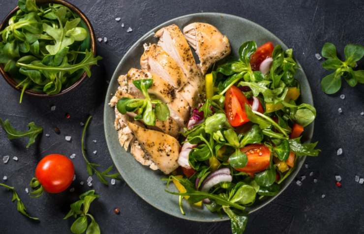 piatto di petto di pollo con insalata e pomodori